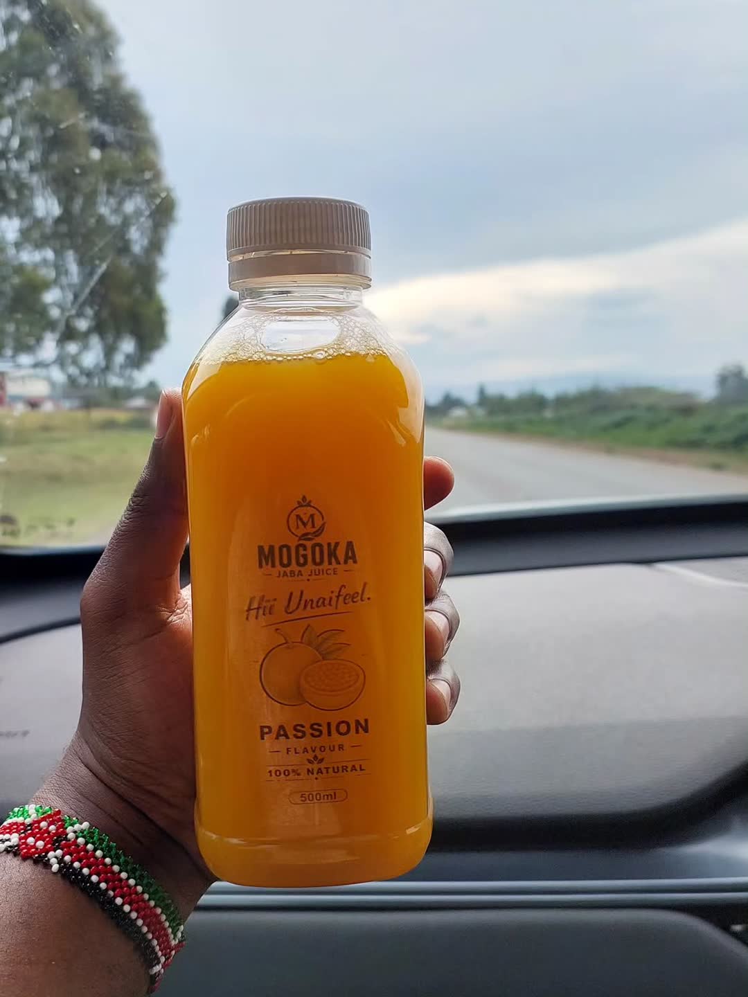 A Passion bottle held up on a Kenyan roadside